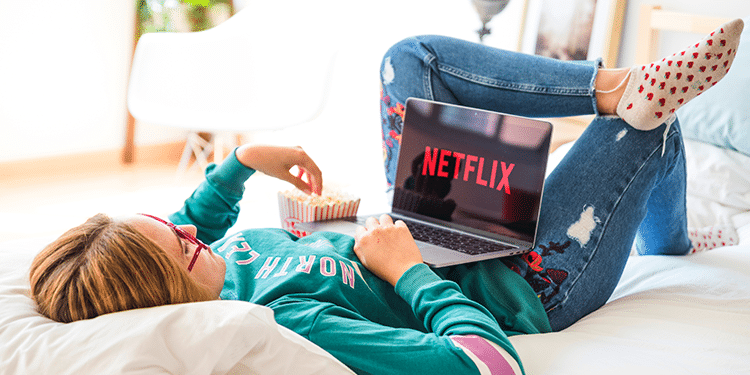 Mujer acostada con notbook en Netflix